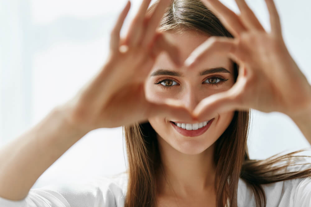 Young woman smiling while making a heart with her hands