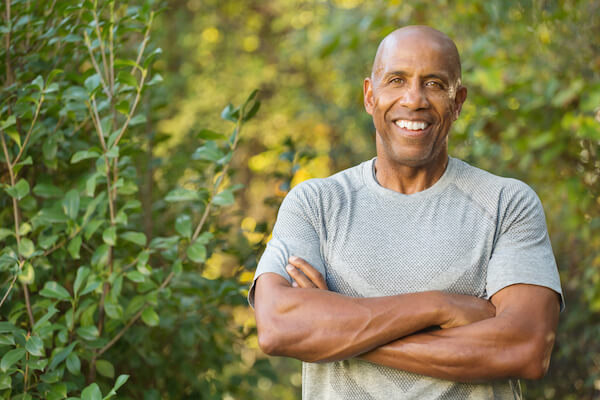 Older man outside, smiling with arms crossed